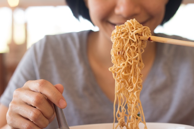 写真 若いアジアの女性は麺を食べている、女性は朝食を食べている