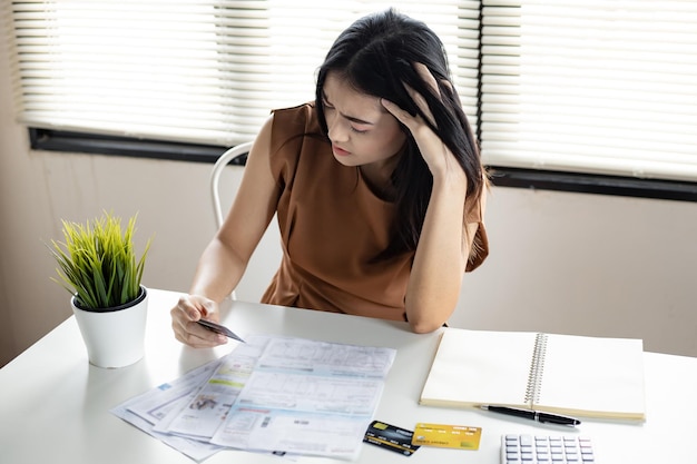 Photo young asian woman is stressed and overthink by debt from many credit cards and bills. concept of financial problem. women figured out a way out of debt at hand.