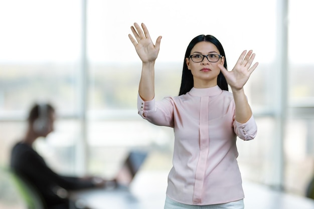 Young asian woman is zooming in objects on imaginary virtual screen for copy space