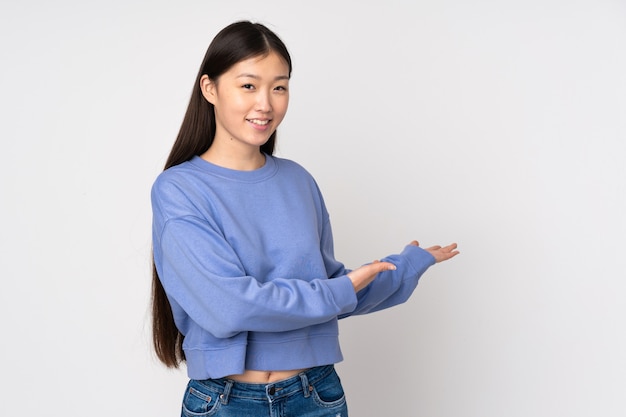 Young asian woman isolated on background extending hands to the side for inviting to come