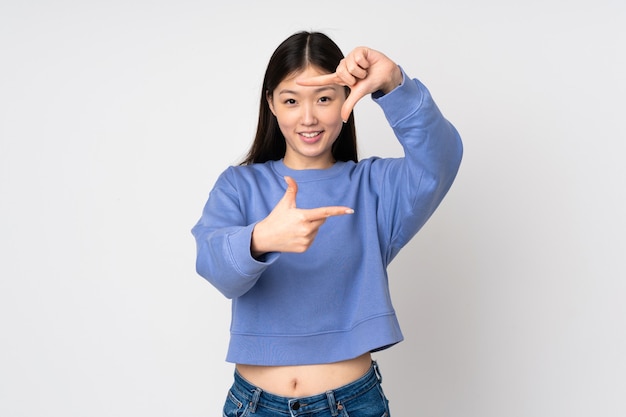 Young asian woman isolated on background focusing face. Framing symbol