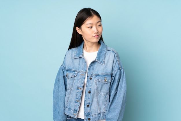 Young asian woman isolated on background having doubts while looking side