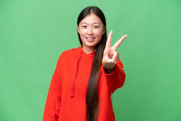 孤立した背景の上の若いアジアの女性が緊張して前に手を伸ばす