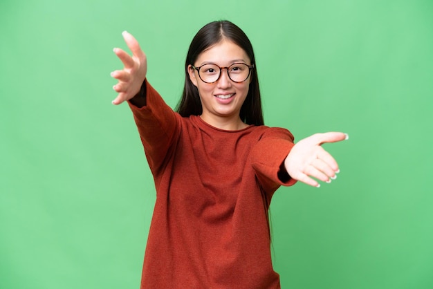 Young Asian woman over isolated background presenting an idea while looking smiling towards