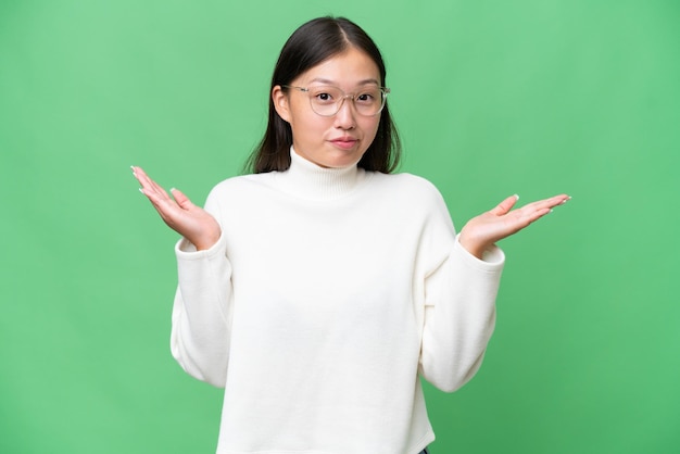 Young Asian woman over isolated background shouting and announcing something