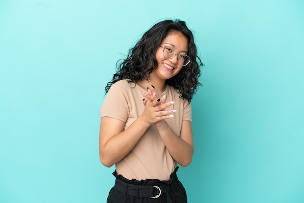 Young asian woman isolated on blue background applauding after presentation in a conference