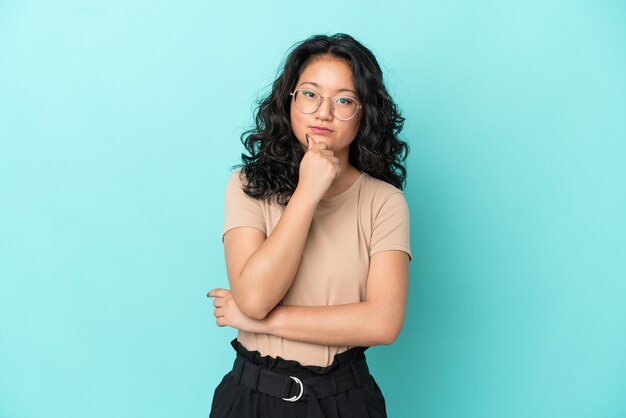 Young asian woman isolated on blue background thinking an idea while looking up