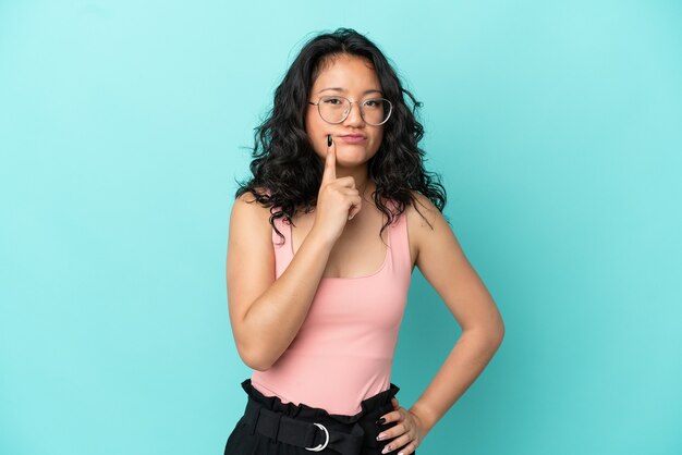 Young asian woman isolated on blue background and thinking