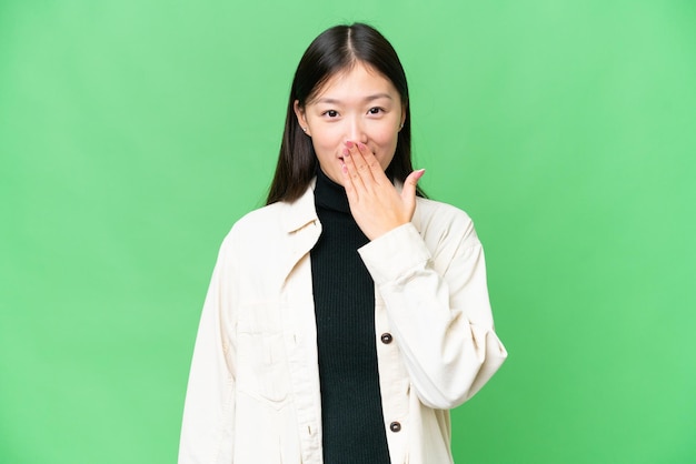 Young Asian woman over isolated chroma key background happy and smiling covering mouth with hand