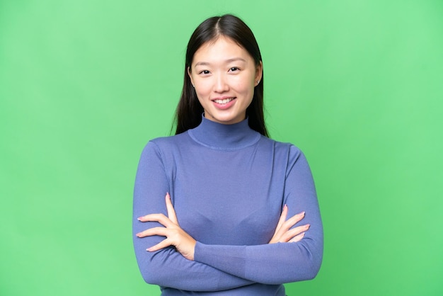 Young Asian woman over isolated chroma key background keeping the arms crossed in frontal position