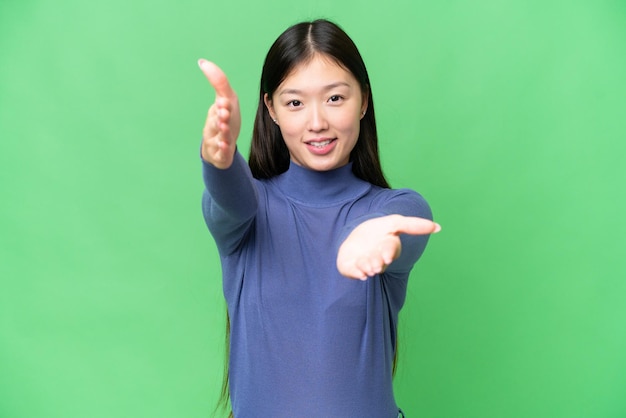 Young Asian woman over isolated chroma key background presenting and inviting to come with hand