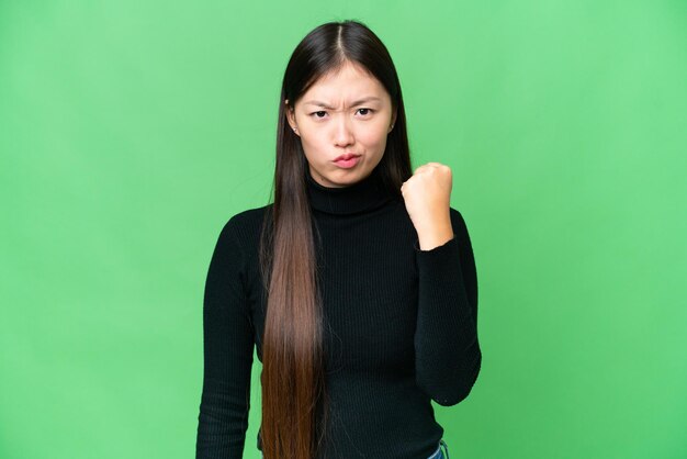 Молодая азиатка на изолированном фоне хроматического ключа с несчастным выражением лица