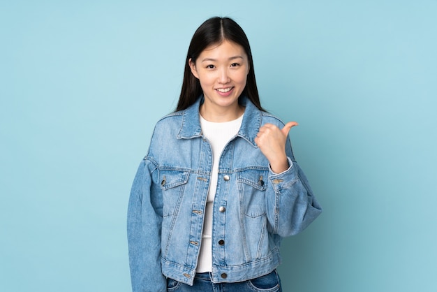 Young asian woman isolated on pointing to the side to present a product