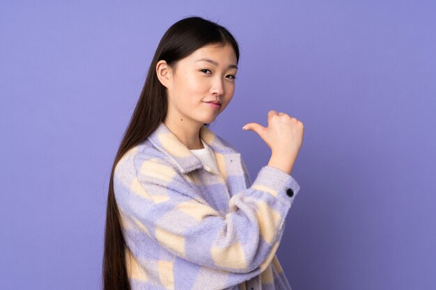 Young asian woman isolated on purple wall proud and self-satisfied