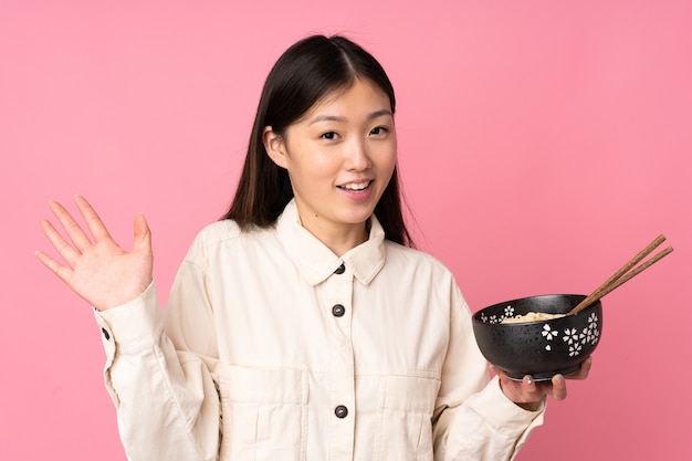 Young asian woman isolated saluting with hand with happy expression while holding a bowl