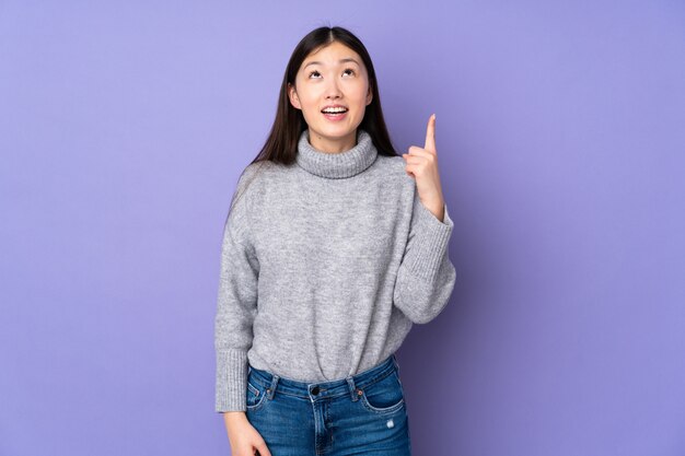 孤立した壁を上向きと驚きの上の若いアジア女性