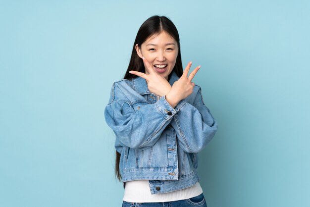 Young asian woman isolated on wall smiling and showing victory sign