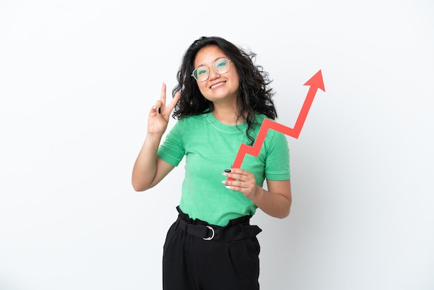 Young asian woman isolated on white background holding a catching a rising arrow and celebrating a victory