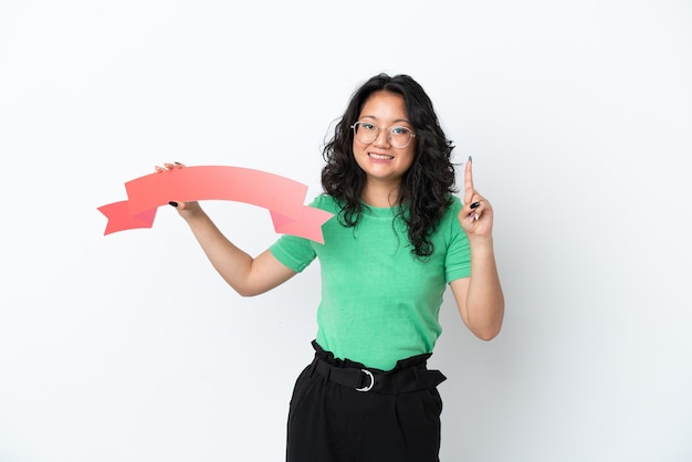 Young asian woman isolated on white background holding an empty placard and pointing up