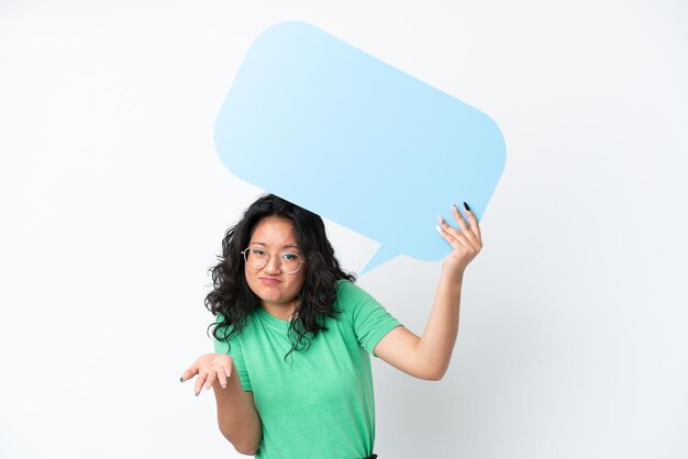 Photo young asian woman isolated on white background holding an empty speech bubble and having doubts