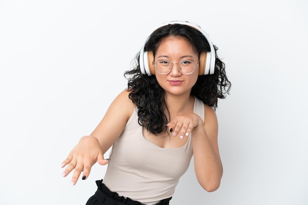 Young asian woman isolated on white background listening music and dancing