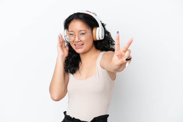 Young asian woman isolated on white background listening music and singing