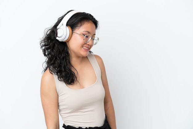 음악을 듣고 흰색 배경에 고립 된 젊은 아시아 여자