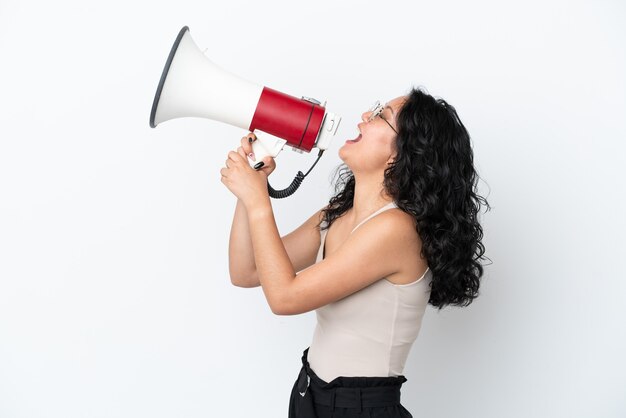 Young asian woman isolated on white background shouting through a megaphone to announce something in lateral position