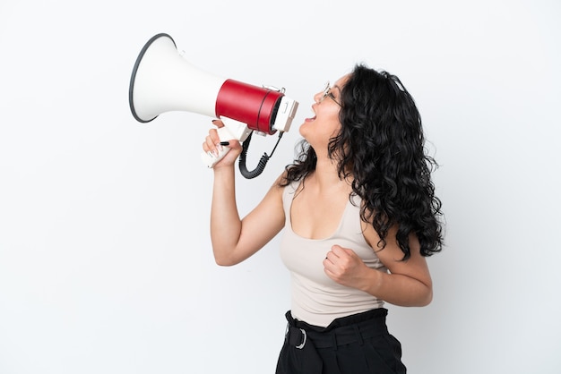 Young asian woman isolated on white background shouting through a megaphone to announce something in lateral position