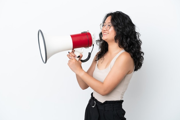 Young asian woman isolated on white background shouting through a megaphone to announce something