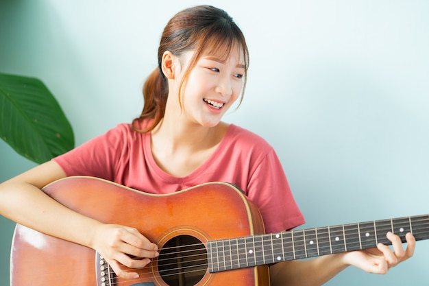 Young Asian woman learning guitar at home