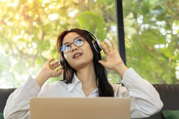 Photo young asian woman listening her favorite song on laptop copy space music break