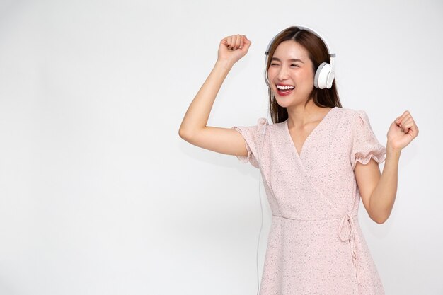 Young Asian woman listening music with headphones isolated  