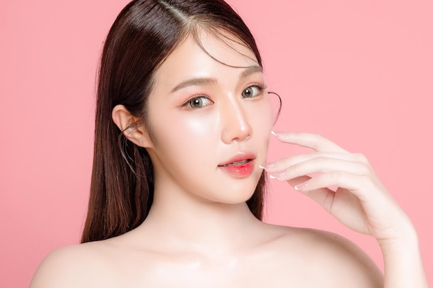 Young asian woman long hair with natural makeup on face have plump lips and clean fresh skin on isolated pink background portrait of cute female model in studio facial treatment cosmetology