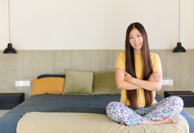 興奮して驚いたように見える若いアジア人女性は、両手を頭に向けて口を開け、幸運な勝者のように感じています