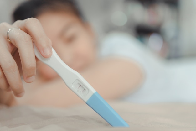 Young asian woman looking at pregnancy test in happiness