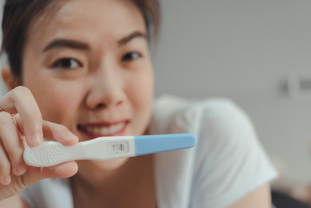 Young asian woman looking at pregnancy test in happiness