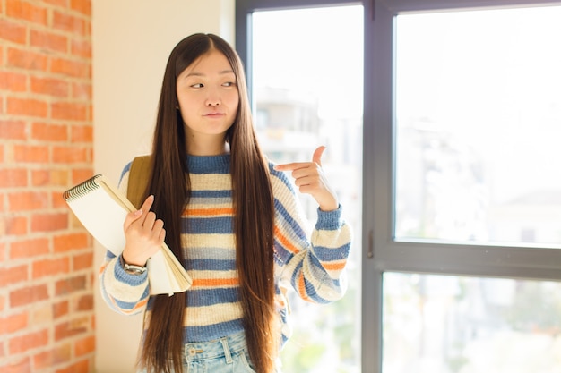 두 손으로 가슴을 자랑스럽고 긍정적이고 캐주얼 가리키는 찾고 젊은 아시아 여자