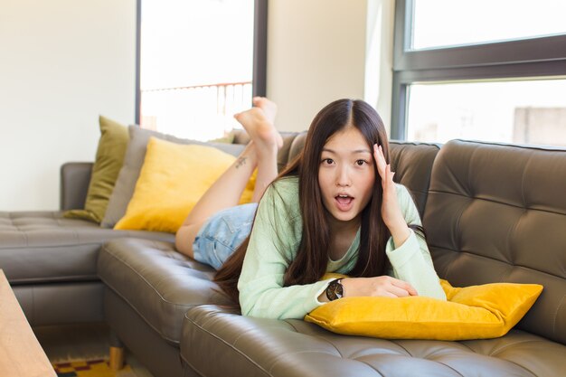 Young asian woman looking surprised, open-mouthed, shocked, realizing a new thought, idea or concept