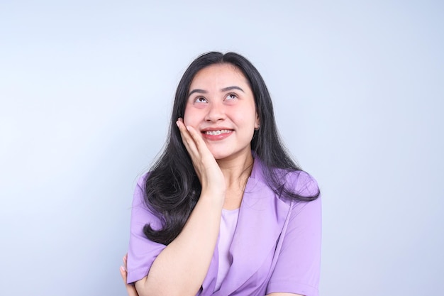 Young Asian woman looking up while smiling isolated on grey background