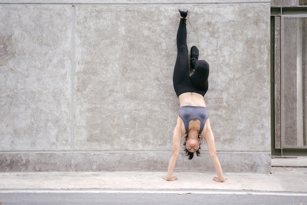 Молодая азиатская женщина делает handstand вверх ногами в упражнении. концепция спортсмена фитнеса