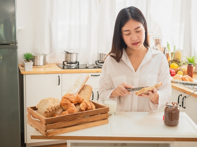 젊은 아시아 여자 샌드위치를 만들고 부엌에서 빵을 먹는