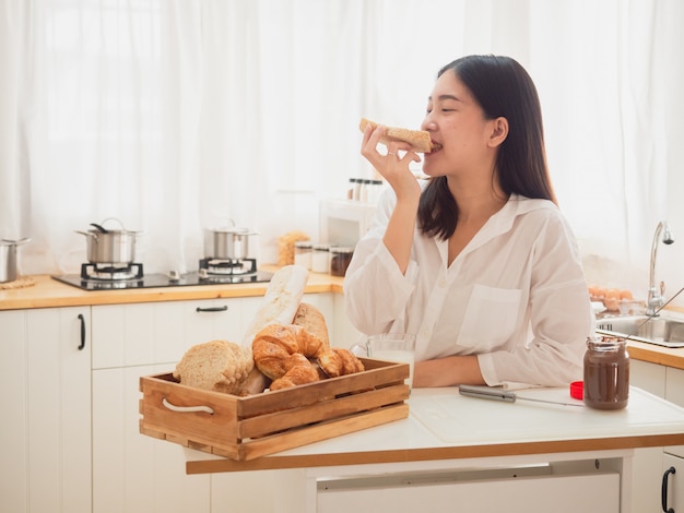 젊은 아시아 여자 샌드위치를 만들고 부엌에서 빵을 먹는