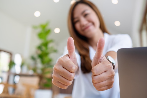 A young asian woman making and showing thumbs up hand sign