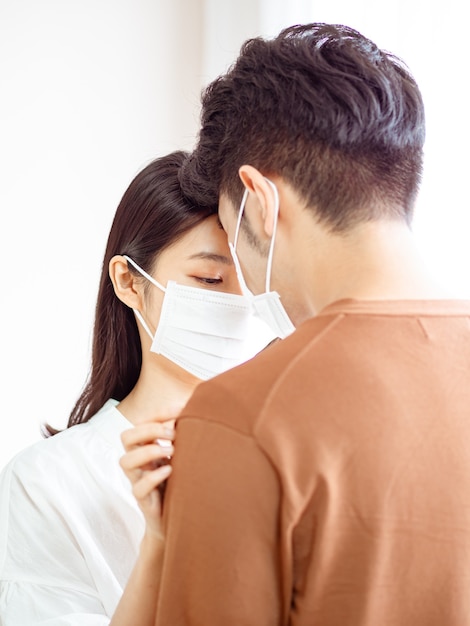 Young asian woman and man wearing Surgical mask at home