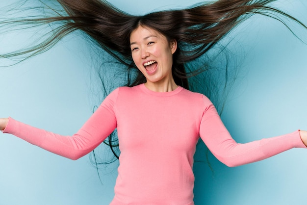 Young asian woman moving hair isolated on blue background