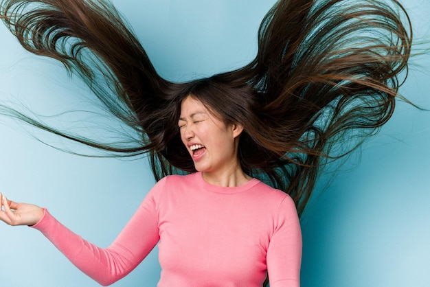 Photo young asian woman moving hair isolated on blue background