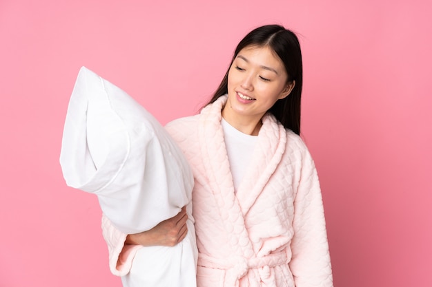 Young Asian woman in pajamas on pink wall with happy expression