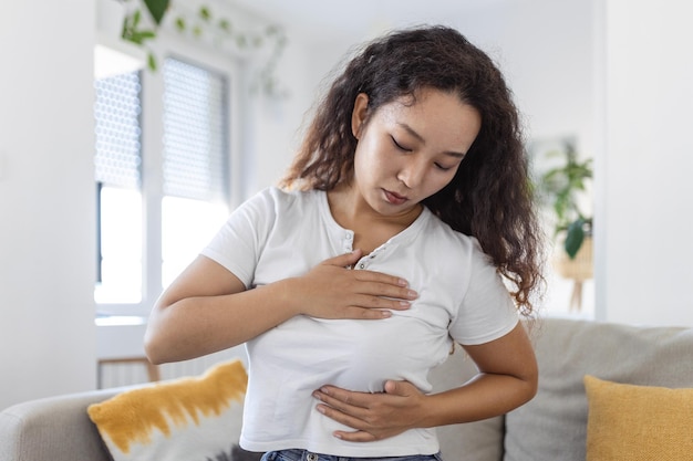 Young Asian woman palpating her breast by herself that she concern about breast cancer