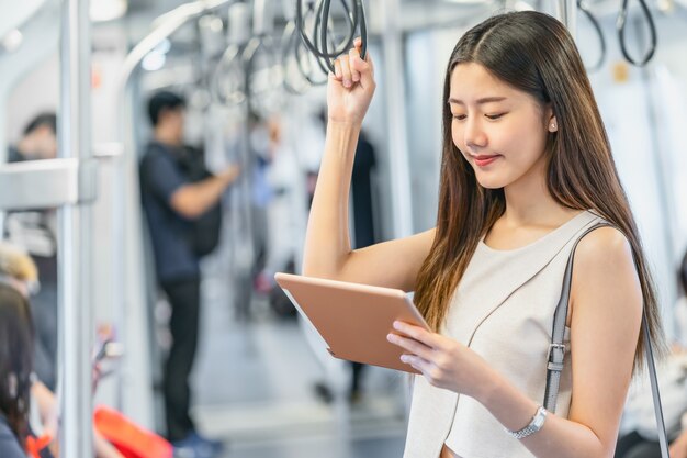 Young Asian woman passenger using mutimedia player via Technology tablet